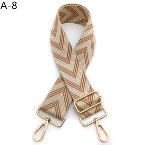 Close-up of adjustable woven shoulder strap with brown chevron pattern and gold metal hooks