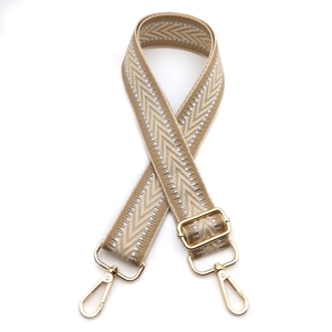 Detail of adjustable khaki woven bag strap with silver V-pattern and gold metal lobster clasps