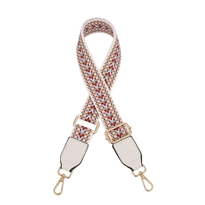 Close-up of adjustable woven shoulder strap with gold metal hooks and white faux leather
