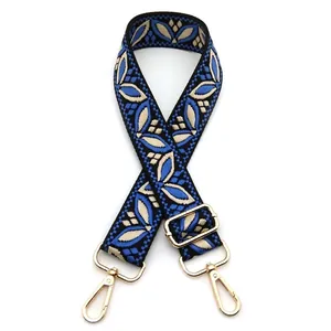 Detail of ethnic embroidered blue and beige woven bag strap with golden metal lobster clasps