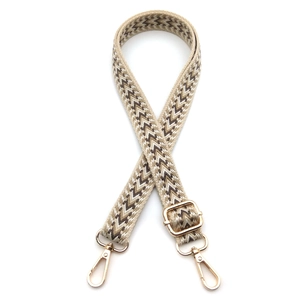 Close-up of beige jacquard bag strap with arrow pattern and gold metal buckles
