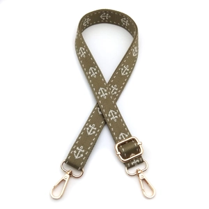 Detail of olive green jacquard bag strap with white anchor pattern and gold hardware