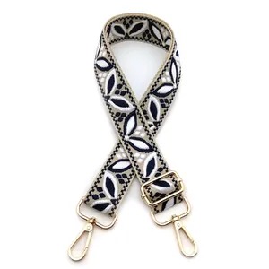Close-up of beige ethnic bag strap with navy floral jacquard and gold lobster clasps