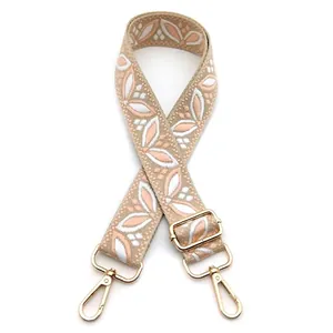Detail of adjustable floral jacquard bag strap with pink embroidery and gold hardware