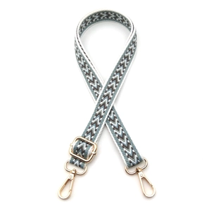 Detail of adjustable bohemian woven bag strap with geometric patterns and gold metal clips