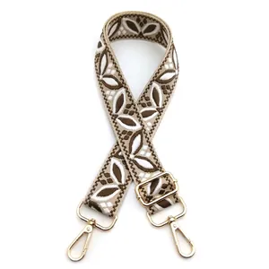 Detail of floral jacquard bag strap with golden swivel hooks and adjustable buckle
