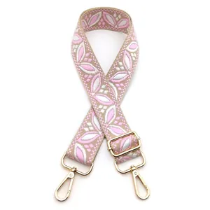 Detail of adjustable floral embroidered bag strap in pink and white with gold metal clips