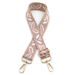 Detail of pink and white floral embroidered strap with golden metal swivel hooks