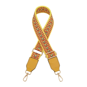 Detail of colorful geometric woven strap with yellow leather ends and gold metal hooks