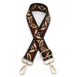 Detail of adjustable woven bag strap with retro leaf patterns and gold metal hardware