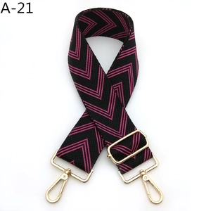 Detail of adjustable woven shoulder strap with pink and black chevron pattern and gold metal hooks