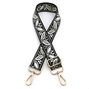 Close-up of ethnic floral jacquard bag strap with adjustable gold-tone metal buckles