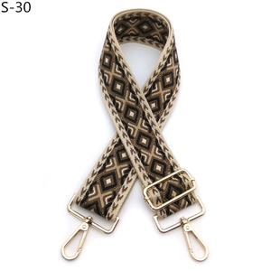 Detail of jacquard geometric pattern strap with polished gold-tone metal buckles