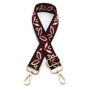 Detail of adjustable bag strap featuring red and white ethnic floral embroidery and gold hooks
