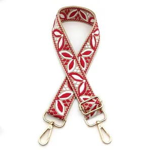 Detail of adjustable ethnic jacquard strap with red floral embroidery and gold metal clips