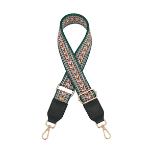 Close-up of adjustable woven shoulder strap with green V-shape pattern and gold metal hooks