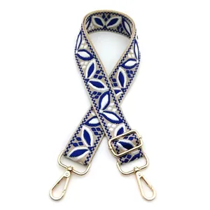 Detail of blue and white ethnic floral embroidery on adjustable bag strap with gold buckle