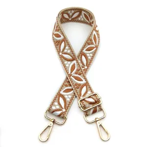 Close-up of bohemian brown leaf embroidery on beige adjustable strap with gold hooks