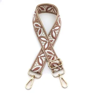 Detail of adjustable wide bag strap featuring retro leaf embroidery and gold metal hardware