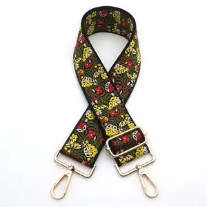 Close-up of ethnic embroidered bag strap with floral patterns and gold metal buckles