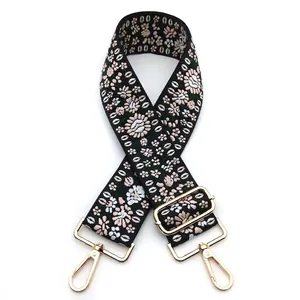 Close-up of floral embroidered bag strap with gold metal hooks and adjustable buckle