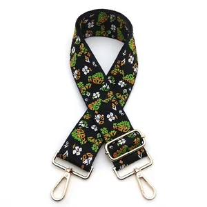 Close-up of ethnic jacquard bag strap with green floral embroidery and gold metal hooks
