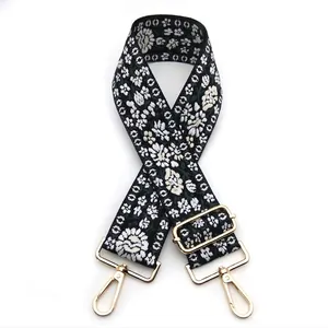 Close-up of floral embroidery on wide shoulder strap with gold metal hooks for handbags