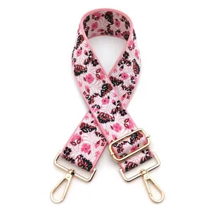 Detail view of floral embroidered wide strap with pink base and golden metal swivel hooks