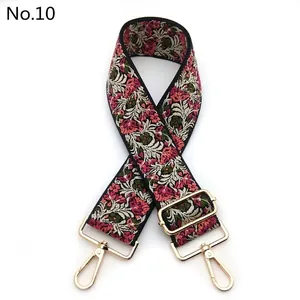 Close-up of floral embroidered wide strap with light gold metal swivel hooks and buckle