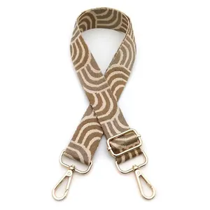 Detail of wide woven shoulder strap with beige and brown geometric waves and gold hooks
