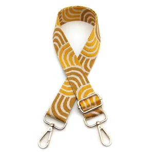 Detail of yellow wave patterned woven strap with golden lobster clasps for bags