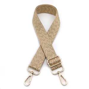 Detail of adjustable beige woven shoulder strap with gold hardware and lobster clasps