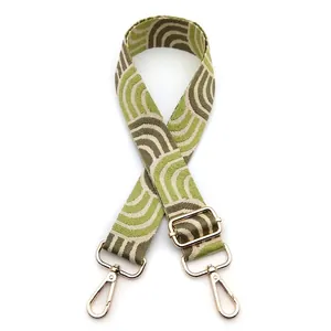 Detail of adjustable green and beige geometric shoulder strap with gold metal lobster hooks