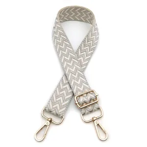 Macro view of adjustable woven shoulder strap with herringbone pattern and gold metal hooks
