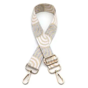 Close-up of wide jacquard strap with cream gray abstract patterns and gold metal buckles