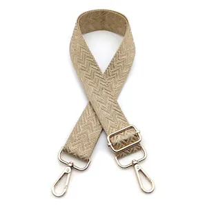 Detail of adjustable woven bag strap with golden lobster clasps and herringbone pattern