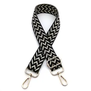 Detail of 3.8cm wide adjustable bag strap with black and white woven pattern and gold clips