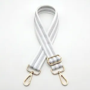 Close-up of white and silver striped woven bag strap with golden metal lobster clasps