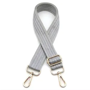 Close-up of light grey chevron patterned bag strap with shiny gold adjustable metal hardware