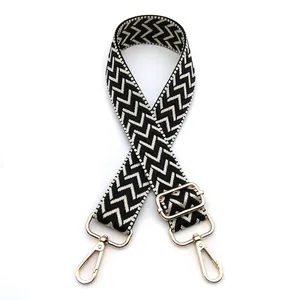 Close-up of black and white chevron bag strap with adjustable golden metal lobster clasps