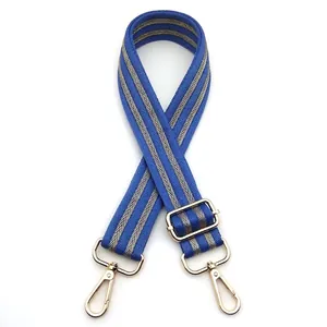Close-up of royal blue woven bag strap with golden chevron pattern and metal hooks