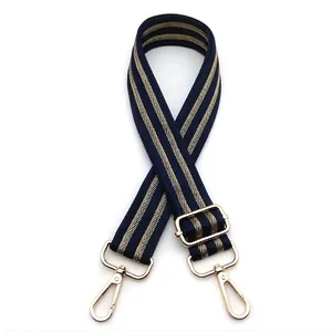 Detail of adjustable navy blue and gold striped woven bag strap with golden lobster clasp