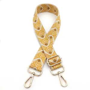 Detail of adjustable guitar strap with beige and yellow geometric diamond pattern and gold hooks