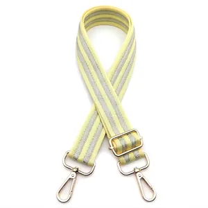 Detail of adjustable yellow and white striped bag strap with gold lobster claw hooks