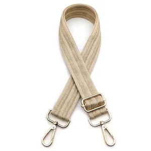 Close-up of adjustable beige herringbone woven bag strap with gold metal buckles