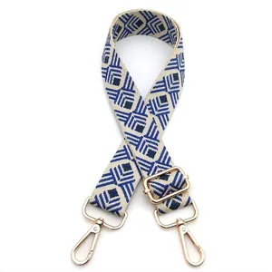 Detail of blue and beige geometric diamond pattern guitar strap with gold metal hooks