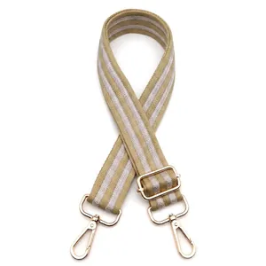 Macro detail of herringbone woven bag strap in orange and grey with golden metal hooks