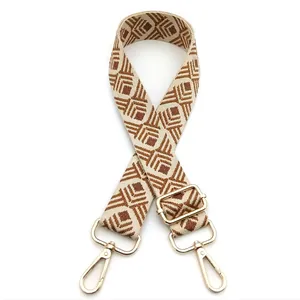 Detail of adjustable woven shoulder strap with brown geometric patterns and gold clasps