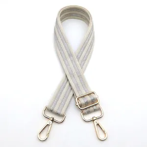 Close-up of adjustable cream and silver shoulder strap with polished gold metal buckles