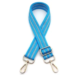 Detail of blue and silver herringbone woven bag strap with golden metal swivel hooks